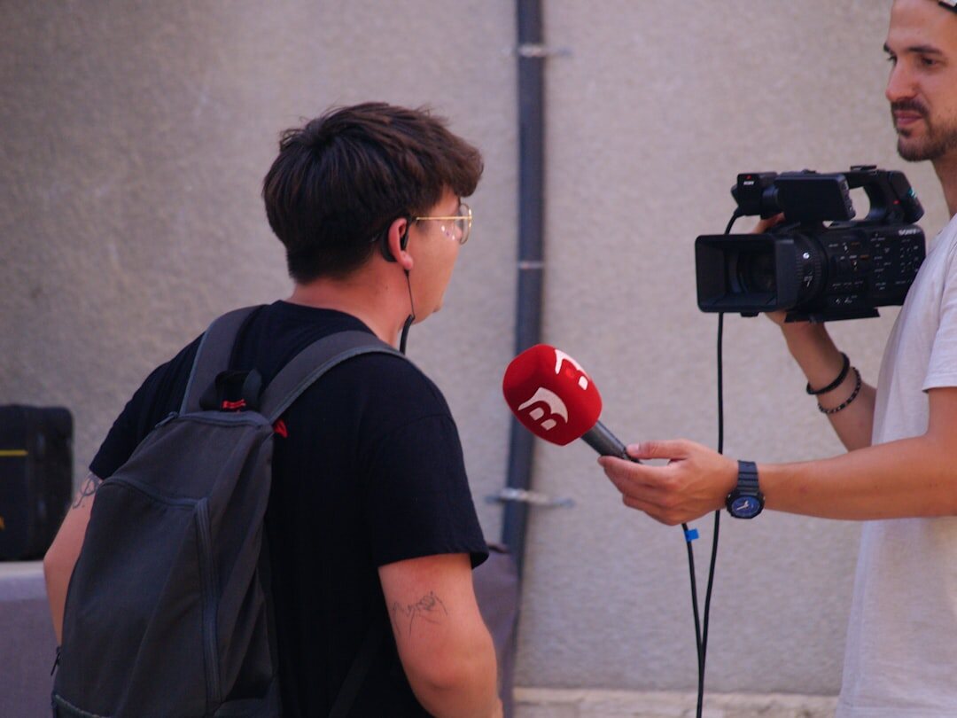 Field journalist with professional camera and microphone at outdoor news location